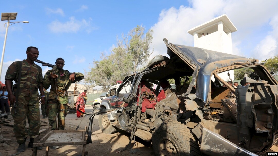 Somali policemen look at the wreckage of a car at the scene of an explosion following an attack in Somalia's capital Mogadishu, March 9, 2016. 
