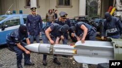 Foto yang dirilis oleh Kepolisian Turino, Italia, pada 15 Juli 2019, tampak para petugas kepolisian menggotong misil yang merupakan salah satu amunisi dan senjata yang disita oleh satuan polisi khusus. (Foto: AFP)