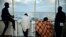 Migrants look at the coastline as they stand aboard a rescue ship, off the coast of Sicily, May 14, 2018. 