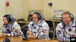 Actress Yulia Peresild, left, film director Klim Shipenko, right, and cosmonaut Anton Shkaplerov speak with their relatives through a safety glass prior the launch at the Baikonur Cosmodrome, Kazakhstan, Oct. 5, 2021.