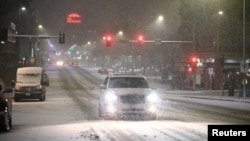 A car drives by as it snows in Des Moines, Iowa, Jan. 8, 2024. 