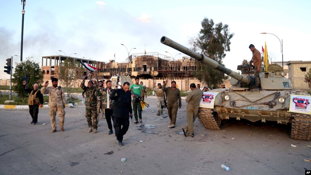 Pasukan keamanan Irak dan aliansi militan Syiah merayakan kemenangan mereka di depan gedung pemerintah di Tirkit, 130 kilometer utara Baghdad, Irak, 31 Maret 2015 (AP Photo/Khalid Mohammed)