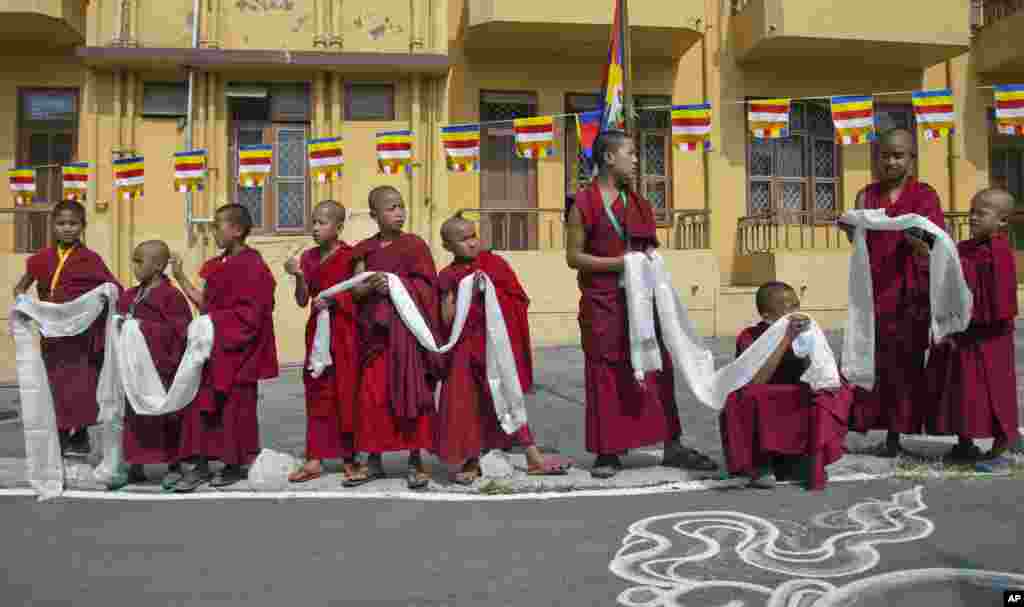 Novice exile Tibetan monks wait with ceremonial scarves to welcome their spiritual leader the Dalai Lama before he arrives to give a religious talk at the Gyuto Monastery in Dharmsala, India.