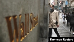 FILE - A man wears a protective mask as he walks on Wall Street during the coronavirus outbreak in New York.