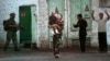 FILE - A resident with a child walks by a soldier during an uprising in Andijan, Uzbekistan, May 13, 2005. A rare protest by crowds in Babur Square who were demanding an end to corruption and injustice ended with hundreds dead in torrents of blood.