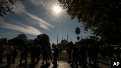 FILE—Pedestrians walk near Sultan Ahmed mosque during a partial solar eclipse in Istanbul, Turkey, October 25, 2022