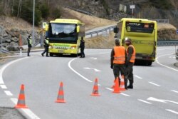 FILE - Police at a roadblock stop a bus from driving in and out of the Paznauntal, near Landeck, Austrian province of Tyrol, March 14, 2020.