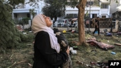 FILE - A woman reacts while holding a pillow as she stands amidst debris outside the site of the Ahli Arab Hospital in central Gaza on Oct. 18, 2023, in the aftermath of an overnight strike there.