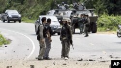 Thai security personnel inspect the site of the bomb attack on a patrol in which two policemen were wounded in the southern Yala province . In a separate attack, suspected Muslim separatists killed four soldiers and wounded five others, 20 Jan 2011.