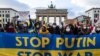 Demonstrators display a banner in the colors of the Ukrainian flag during a protest at Berlin's Brandenburg Gate on January 30, 2022. (John MACDOUGALL / AFP) 