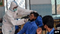 Un agent de santé prélève un échantillon sur un élève pour tester le coronavirus dans un lycée public à Lahore, au Pakistan, le 1er octobre 2020.