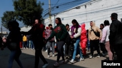 Migrantes, en su mayoría de Haití, Cuba y Venezuela, se reúnen afuera de la Comisión Mexicana de Ayuda a Refugiados (COMAR), mientras esperan en fila para regularizar su situación migratoria en el país, en la Ciudad de México, México, el 24 de enero de 2025.