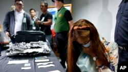 Agnes Alexandra (kanan) duduk di dekat delapan kilogram obat terlarang metamfetamin hidroklorida lokal (shabu) yang disita darinya dalam penerbangan dari Siem Reap, Kamboja, Senin, 7 Oktober 2019 di Bandara Internasional Ninoy Aquino, Manila, Filipina.