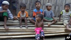 In this March 17, 2017, image made from video, Rosmaida Bibi, center foreground, suffering from severe malnutrition, sits on a pile of bamboo trees with other children at the Dar Paing camp, north of Sittwe, Rakhine state, Myanmar.