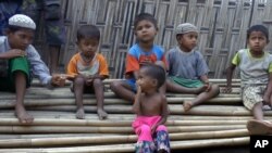 FILE - Children, some suffering from severe malnutrition, sit on a pile of bamboo trees at the Dar Paing camp, north of Sittwe, Rakhine state, Myanmar, March 17, 2017.