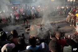 FILE - Bystanders look at the bodies of alleged gang members that were set on fire by a mob after they were stopped by police while traveling in a vehicle in the Canape Vert area of Port-au-Prince, Haiti, Monday, April 24, 2023.