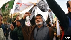 Iraqi mourners wave flags as the coffins of slain Iraqi paramilitary chief Abu Mahdi al-Muhandis, Iranian military commander Qasem Soleimani and eight others towards the Imam Ali Shrine in the shrine city of Najaf in central Iraq during a funeral…