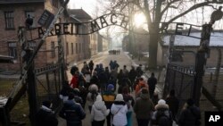 Posetioci prolaze kroz kapiju "Rad oslobađa" na ulazu u memoriljani muzej Aušvic-Birkenau, nekadašnji koncentracioni logor u Poljskoj, 25. januar 2025. (Foto: AP /Oded Balilty)