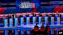FILE - Democratic presidential candidates raise their hands during the Democratic primary debate at the Adrienne Arsht Center for the Performing Arts in Miami, Florida, June 27, 2019.