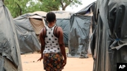 File - A woman who said she was trafficked from Nigeria under false pretenses to work as a sex slave in Burkina Faso's mining sites, walks through a row of tent in the Secaco mining town June 12, 2020. 