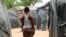 File - A woman who said she was trafficked from Nigeria under false pretenses to work as a sex slave in Burkina Faso's mining sites, walks through a row of tent in the Secaco mining town June 12, 2020. 