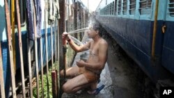 Seorang penumpang kereta India mandi di dalam stasiun di Jammu, India saat suhu mencapai 48 Celcius, Senin (25/5).