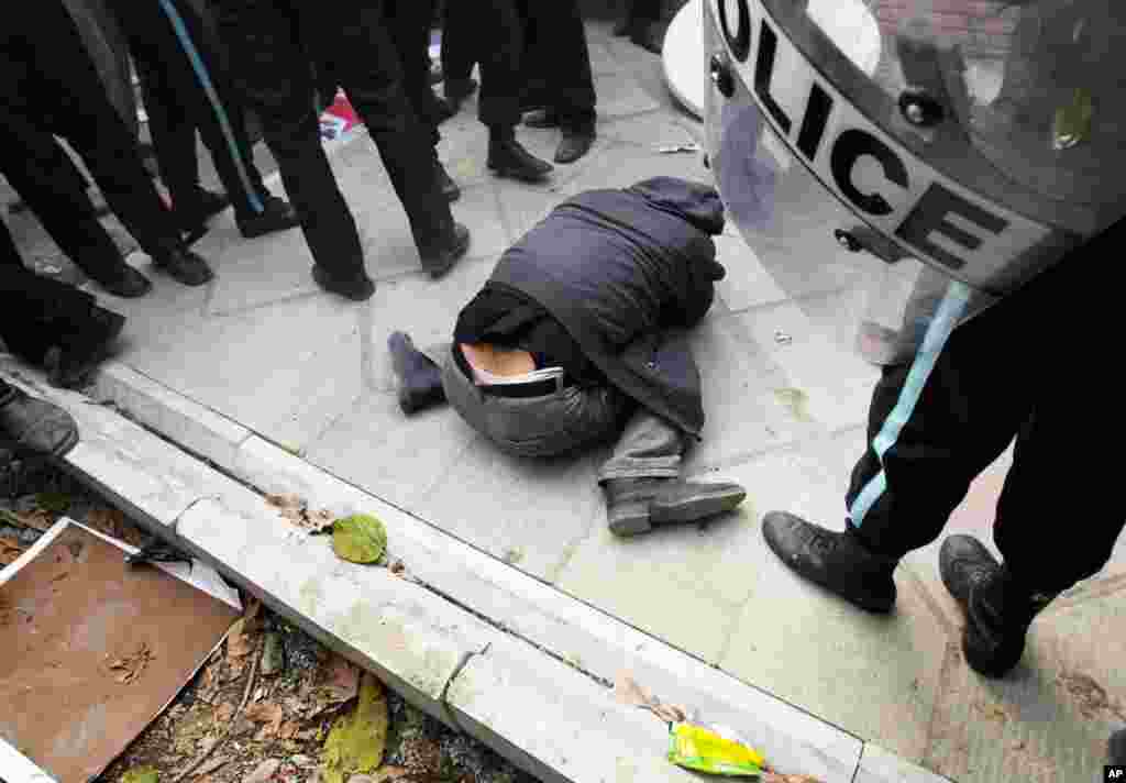 A protester ducks on the ground after being beaten by riot police outside the British embassy. (REUTERS/Stringer)