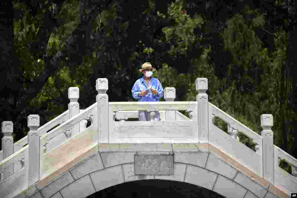 တရုတ်နိုင်ငံ Beijing မြို့ရှိ ပန်းခြံတခုက တံတားတခုမှာ ရပ်နေသူ တဦး။ (ဇွန် ၁၀၊ ၂၀၂၀)