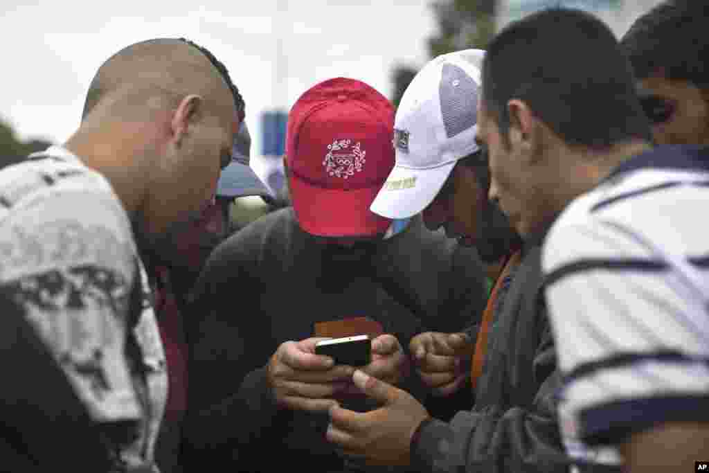 People consult a map on a cell phone as they walk in the direction of Austria, Budapest, Hungary, Sept. 5, 2015. (AP)