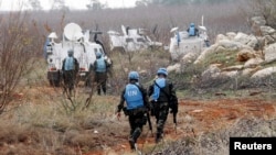 FILE - Troops with the United Nations Interim Force in Lebanon (UNIFIL) inspect the remains of a shell that was launched from Lebanon to Israel, in the southern Lebanese village of Sarada, Dec. 29, 2013.