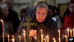 Une femme allume une bougie lors d'un service religieux dans la cathédrale de Saint-Pétersbourg en hommage aux victimes de l'attentat dans le métro de la ville, Russie, le mercredi 5 avril 2017.