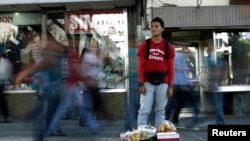 ARCHIVO - Roberto Hurtado, quien no consigue trabajo en su profesión de mecánico de automóviles, vende bocadillos en la céntrica avenida de San José el 27 de enero de 2014.