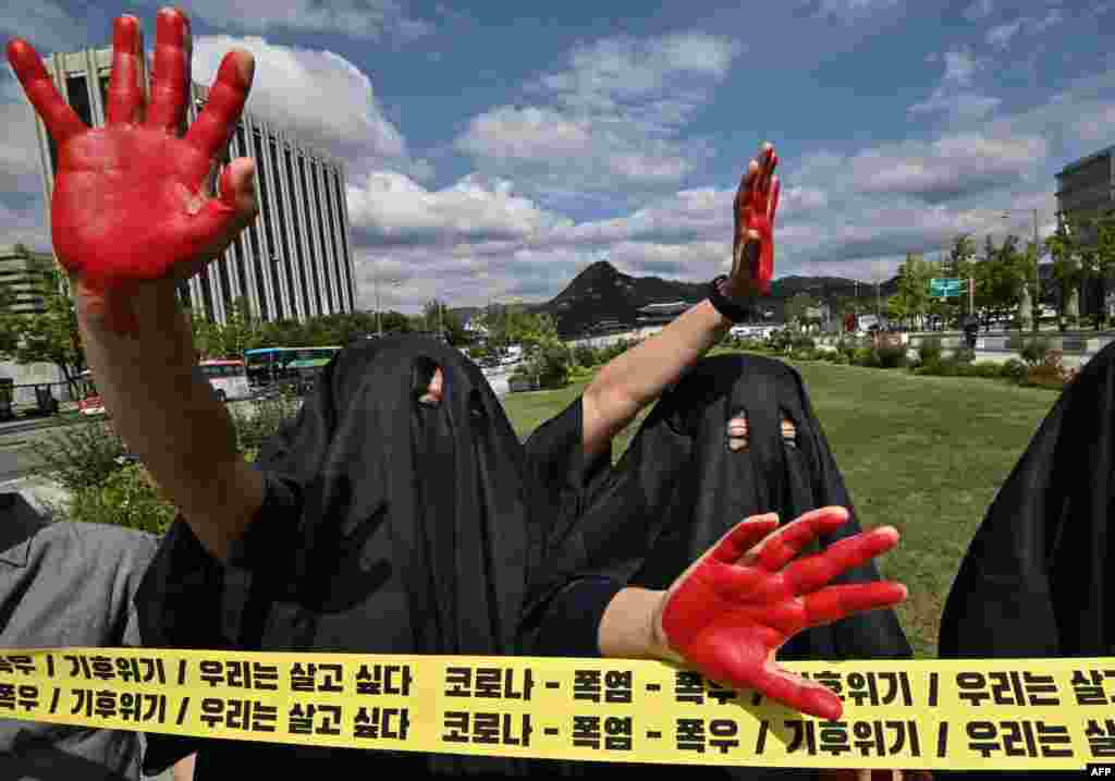 South Korean environmental activists wearing black cloth perform to represent the burning Earth during a protest marking a global climate action day in Seoul.