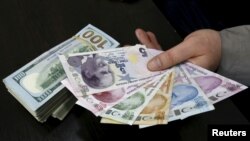 A money changer holds Turkish lira banknotes next to U.S. dollar bills at a currency exchange office in central Istanbul, April 15, 2015. 