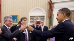 President Barack Obama shares a toast in the Oval Office with the members of his National Security Staff who worked on the New START nuclear arms control agreement, 22 Dec 2010