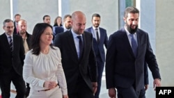 Ministro dos Negócios Estrangeiros francês, Jean-Noel Barrot (C), e a ministra dos Negócios Estrangeiros alemã, Annalena Baerbock (L), a caminhar com o novo governante sírio, Ahmed al-Sharaa.