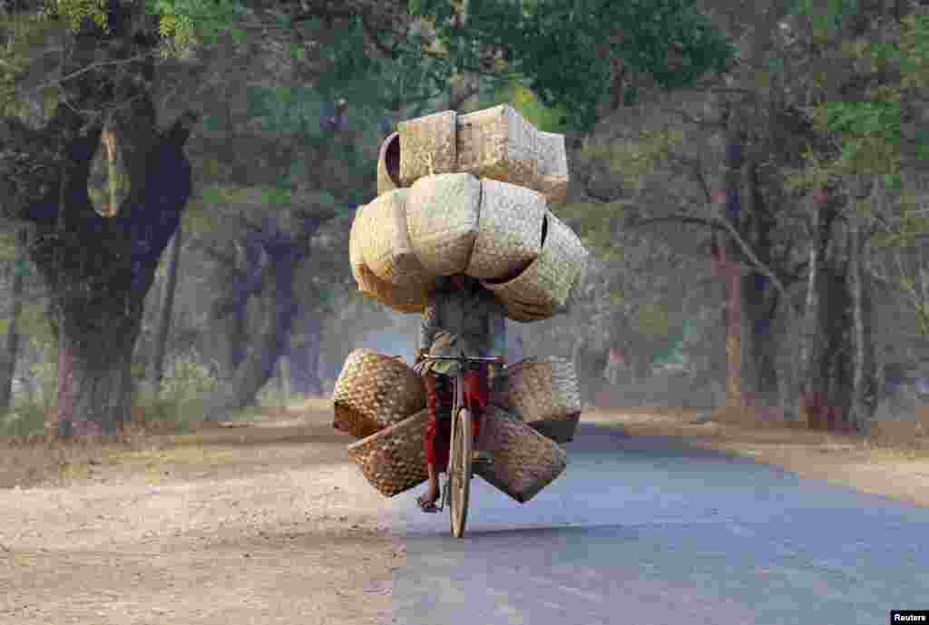 A woman cycles as she carries baskets to sell in a market near Lapdaung mountain in Sarlingyi township, Burma. 