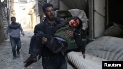 A man carries an injured boy in the rebel-held besieged town of Hamouriyeh, eastern Ghouta, near Damascus, Syria, Feb. 21, 2018.