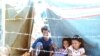 A Cambodian family gathered under a tarp in Sa Keo province, Thailand, in November, 1979.