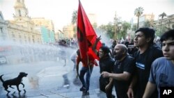 Polisi anti huru hara menyemprotkan air untuk memubarkan para pengunjuk rasa yang berpartisipasi dalam demo KTT Rakyat yang diselenggarakan oleh serikat buruh dan gerakan sosial kiri. Demo ini menentang pelaksanaan KTT 60 negara yang dijadwalkan akan diselenggarakan akhir pekan ini di Santiago, Chile (25/1).