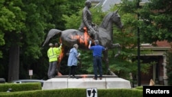 Trabajadores municipales intentan remover la pintura sobre un monumento al soldado confederado John B. Castleman que fue vandalizada el sábado por la noche en Louisville, Kentucky.