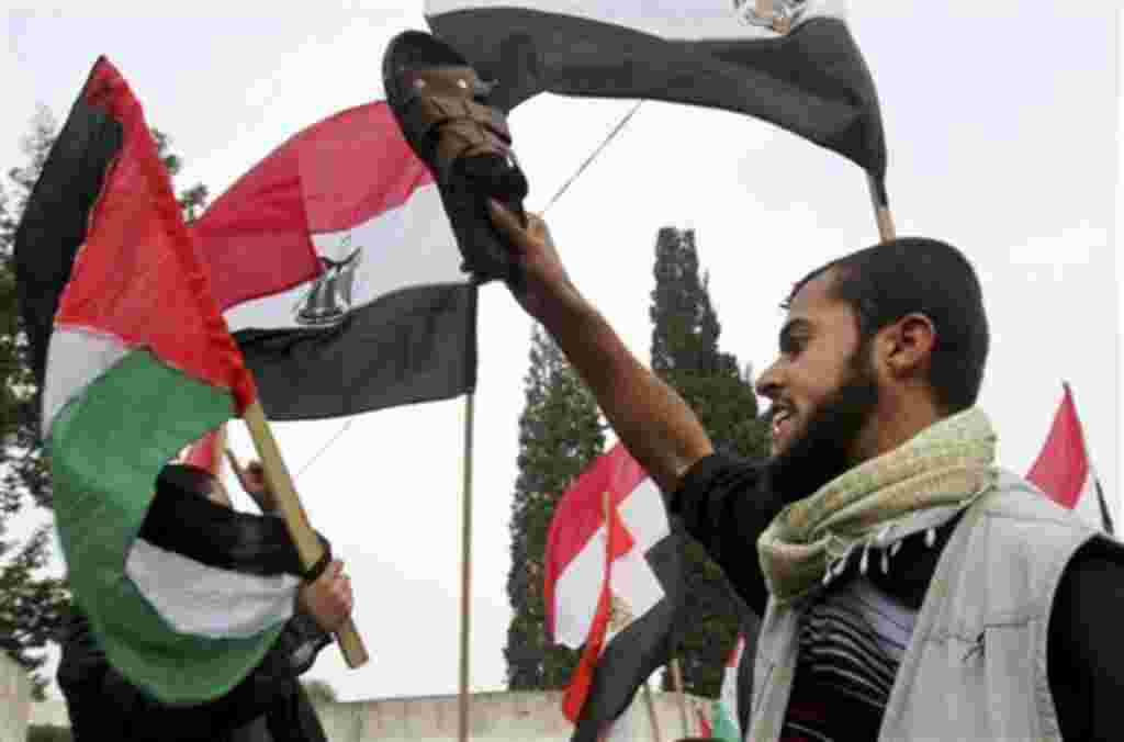 A Palestinian protester holds a shoe as others wave Palestinian and Egyptian flags during a demonstration calling for the removal of Egyptian President Hosni Mubarak in Gaza City, Feb 3, 2011