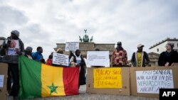 FILE - Demonstrators hold banners reading "Macky Sall dictator: get out!" and "Free Senegal, we do not touch the Constitution" in a protest against human rights violations in Senegal at the Brandenburg Gate (Brandenburger Tor) in Berlin, Germany on February 10,