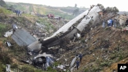 Rescue workers walk among the crash site of a cargo airplane near the airport at Brazzaville in the Republic of Congo on Dec. 1, 2012.