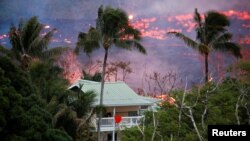 La lava del volcán Kilauea en Hawái fluye cerca de una casa en las afueras de Pahoa, durante una erupción. Mayo 19, de 2018.