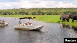 FILE - Foreign tourists in safari riverboats observe elephants along the Chobe riverbank in Chobe National Park, in northern Botswana, March 2005.