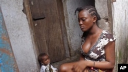 A woman sits with a baby, in the West Point area that has been hardest hit by the Ebola virus spreading in Monrovia, Liberia, Monday, Aug. 25, 2014. A Liberian doctor who was among three Africans to receive an experimental Ebola drug has died, the country's information minister said Monday. (AP Photo/Abbas Dulleh)