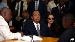 Former Haitian dictator Jean-Claude "Baby Doc" Duvalier, center, attends hearing as companion Veronique Roy sits behind, right, Port-au-Prince, Feb. 28, 2013.