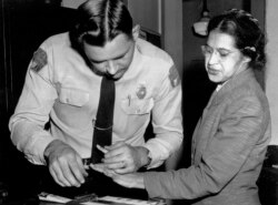 Dalam foto pada 22 Februari 1956 ini, Rosa Parks diambil sidik jarinya oleh polisi Letnan D.H. Lackey di Montgomery, Alabama, setelah menolak menyerahkan kursinya di bus untuk penumpang kulit putih pada 1 Desember 1955.