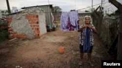 FILE - Claudia Rodrigues, 71, hangs up laundry in front of her home, which is a shipping container, next to a road in Campinas, Sao Paulo state, Brazil, March 22, 2016. Informal settlements set up by those who say they have nowhere else to live are not uncommon in Brazil.